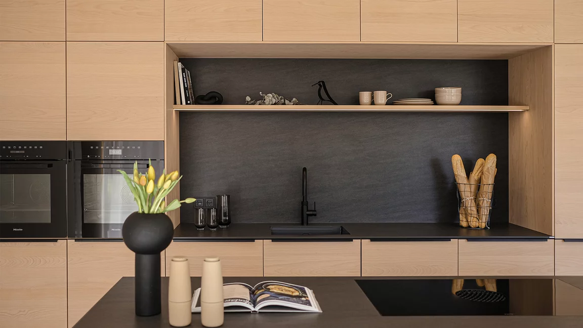 Contrast between dark natural stone and light wooden surfaces of the solid wood kitchen in white beech oil