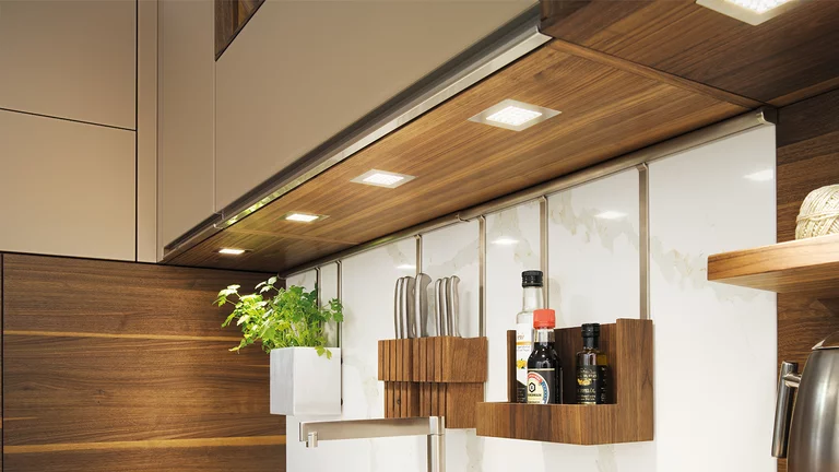 linee Küche in Nussbaum massiv mit Nischenelemente zum Aufhängen, LED-Spots quadratisch und Griffleisten in Edelstahl Finish