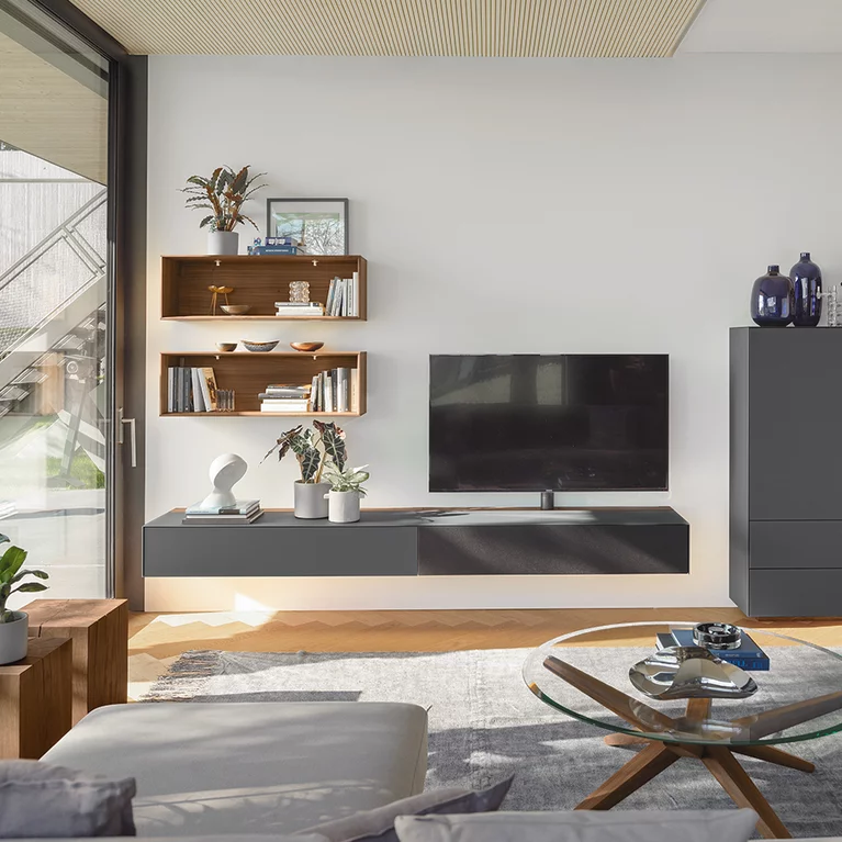 dunkle Wohnwand cubus pure aus Farbglas mit Regale aus Nussbaum massiv und Beleuchtung in modernem Wohnwand