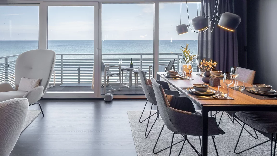 Elegante lui legér Stühle mit Stoffbezug und Drahtgestell an tak Tisch in Nussbaum massiv vor großer Fensterfront mit Meerblick