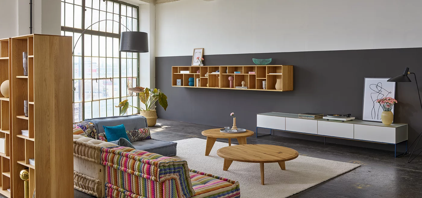 cubus pure wall unit in pearl with midnight blue metal frame, graphic design element in oak and coffee table in wild oak in open-plan living room