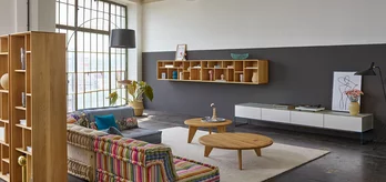 cubus pure wall unit in pearl with midnight blue metal frame, graphic design element in oak and coffee table in wild oak in open-plan living room