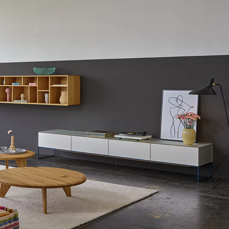 cubus pure Wohnwand in pearl mit nachtblauem Metallrahmengestell, graphic Gestaltungselement aus Eiche und ur Couchtisch aus Eiche Wild in offenem Wohnzimmer