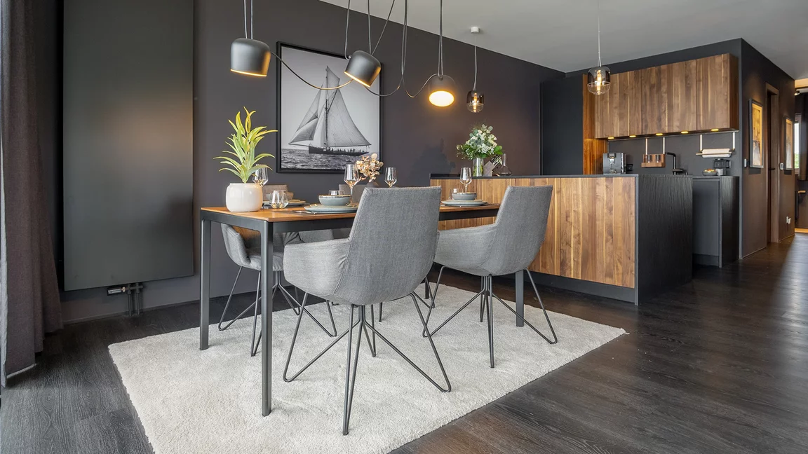 Elegante lui legér Stühle mit Stoffbezug und Drahtgestell an tak Tisch mit schwarzem Metallgestell vor black line Küche in Nussbaum massiv