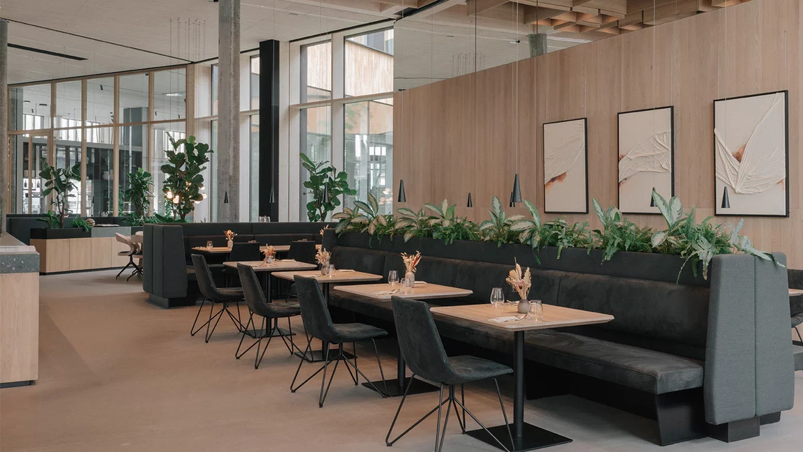 Sideboards und Restaurantsitzplätze mit Massivholztischplatten und lui Stühlen mit hochwertigen Naturlederbezug vor Eiche Massivholzwand in der TEAM 7 Welt