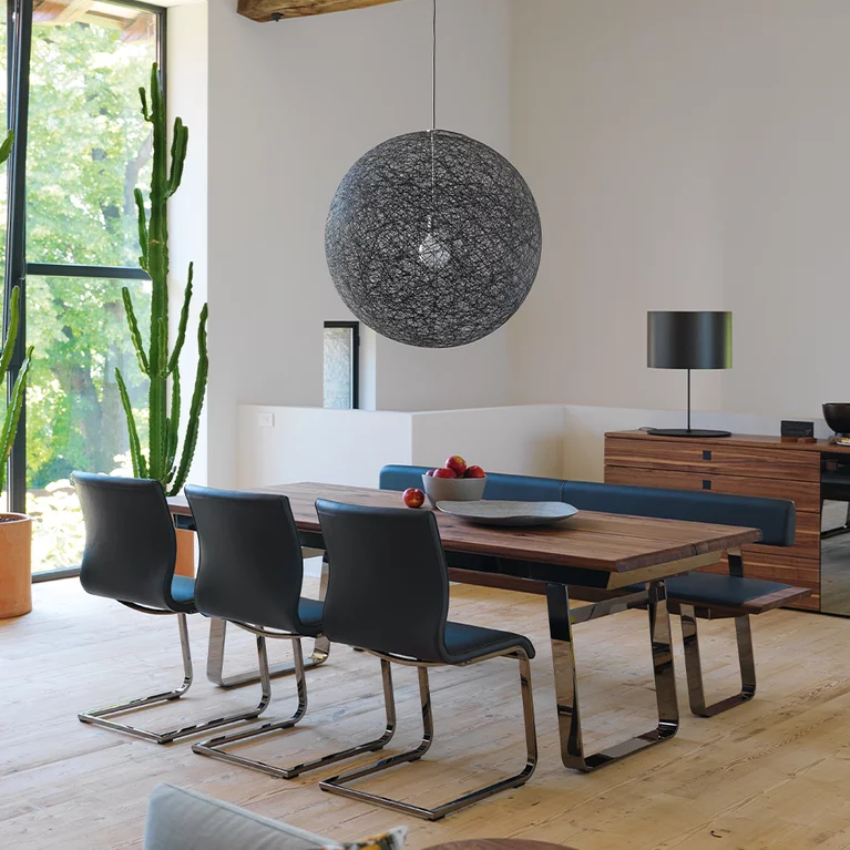 modern dining table nox made of natural wood extendable in walnut with the magnum cantilever chairs upholstered and the nox bench