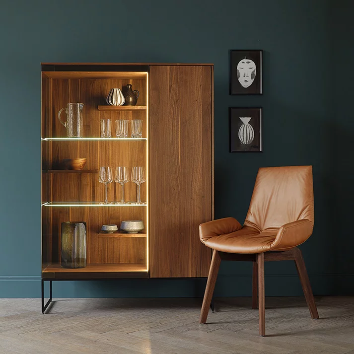 filigno Holzvitrine aus Nussbaum mit Rauchglastür und mit Metallrahmengestell in schwarz matt sowie dem komfortablen lui Stuhl
