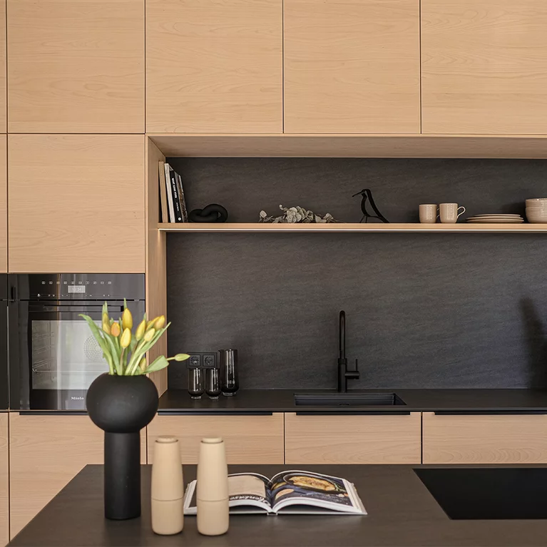Kontrast zwischen dunklem Naturstein und hellen Holzoberflächen der Massivholzküche in Buche Weißöl