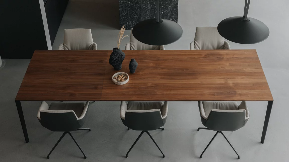 dining table tak made of solid wood and extendable in walnut with metal frame in matt black and the lui léger chair group