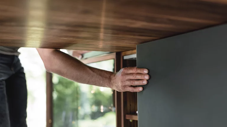 real wood kitchen with sliding door element and coloured glass front, detailed view black line real wood kitchen in walnut with sliding door element with matt black coloured glass front, detailed view