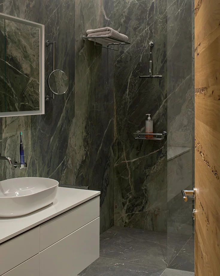 Customised oak Venetian door leads into a bathroom with elegant green marble wall