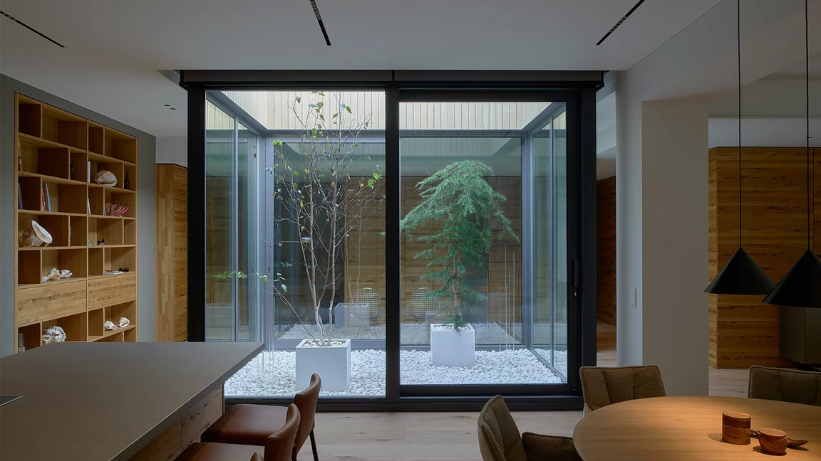 Atrium with trees stylishly surrounded by customised TEAM 7 furniture in Venetian oak and a cubus shelving unit with Venetian oak drawers