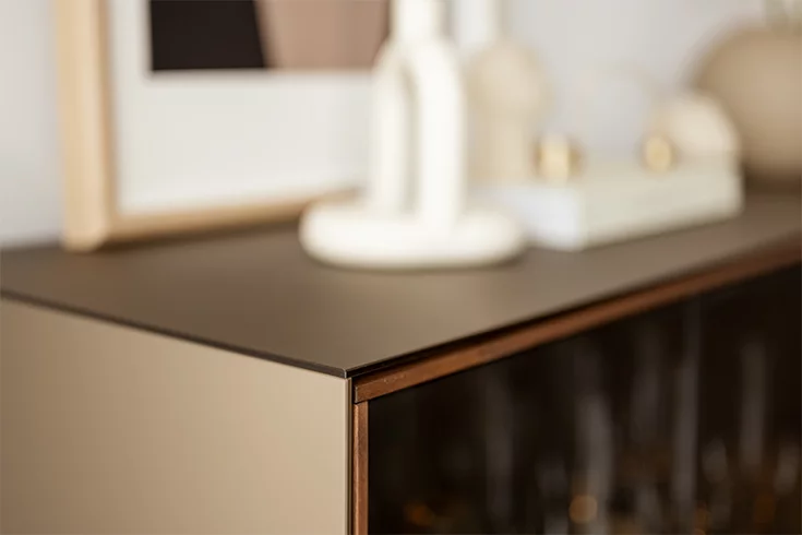 Detailansicht einer cubus pure Holzhighboard in Nussbaum mit Farbglas an Deckplatte und Seiten