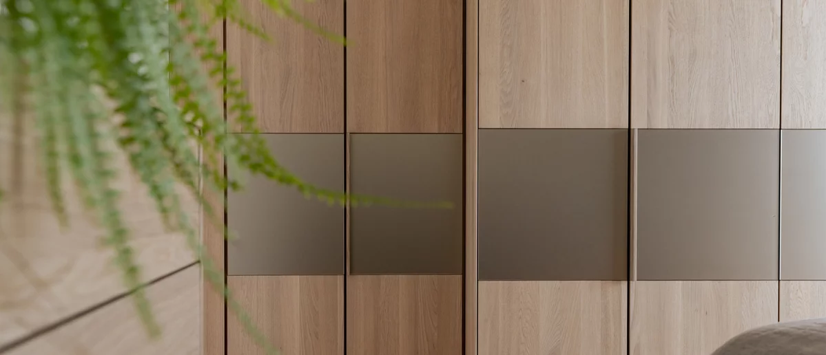 Solid wood hinged door wardrobe valore in oak white oil with integrated wooden handle strips and colored glass elements in bronze