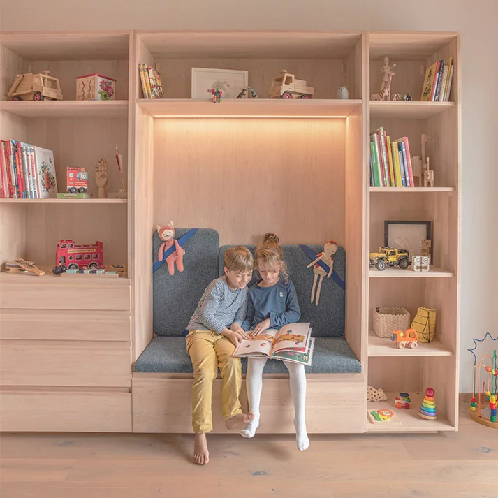 Kleiderschrank kids in Erle Weißöl mit großen Laden und gepolsterten Sitznische beleuchtet