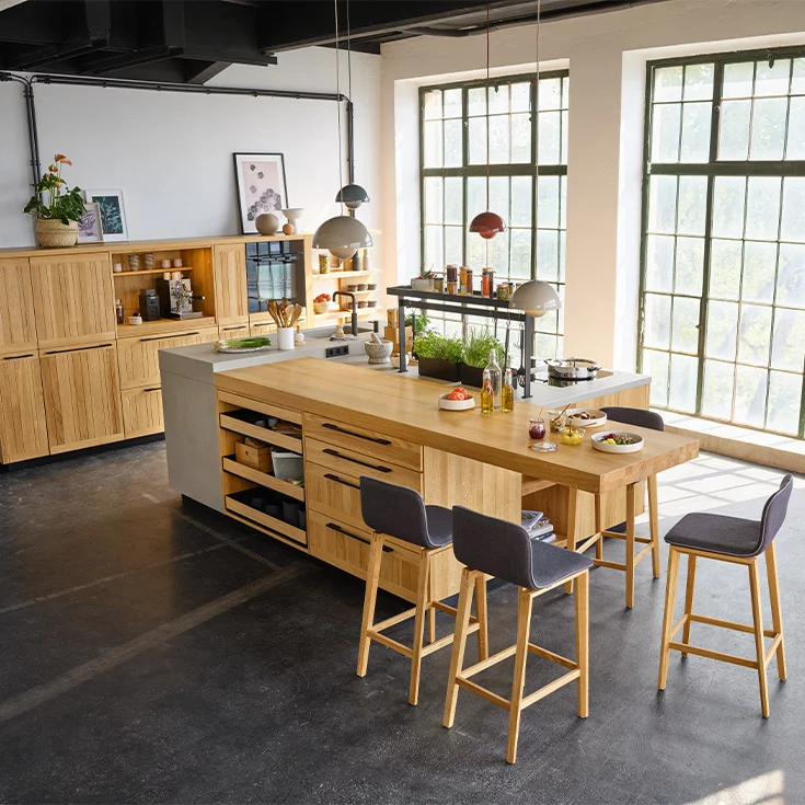 Massivholzküche echt.zeit in Eiche mit Arbeitsplatte in Keramik und integrierter Essbereich mit den ark Barhockern