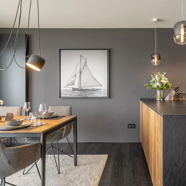 Detailed view of ceramic worktop and side panel in slate look from the black line kitchen next to tak table with lui legér chairs