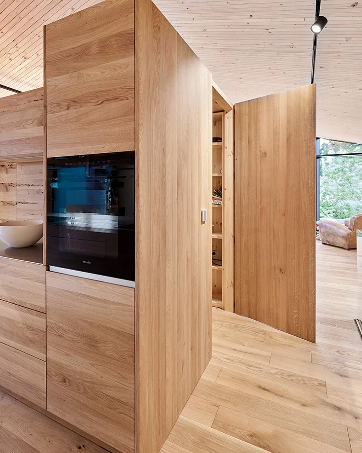 Kitchen planned freely in the room, customised in solid wood with integrated pantry