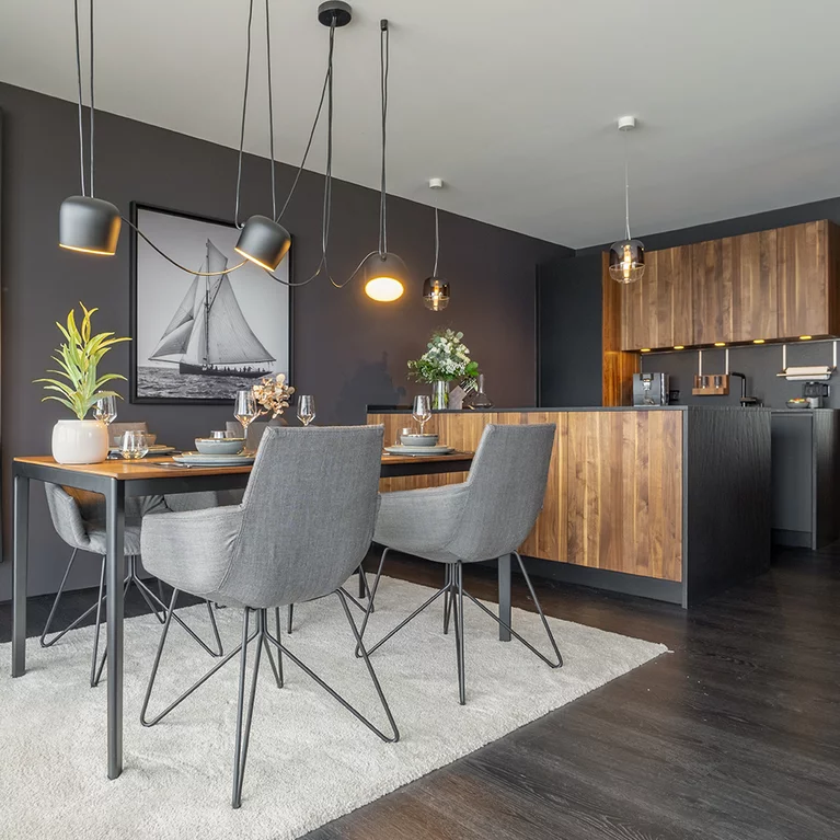 Elegant lui legér chairs with fabric upholstery and wire frame at tak table with black metal frame in front of black line kitchen in solid walnut