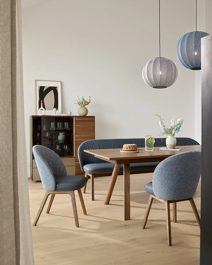 Polsterstühle flor Leder Sitzschale und Stofflehne mit Holzgestell in Nussbaum zusammen mit dem taso Esstisch und der flor Bank