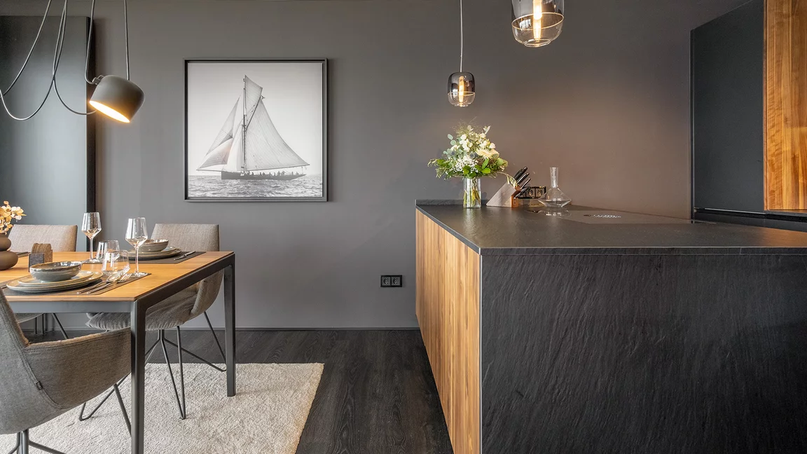 Detailed view of ceramic worktop and side panel in slate look from the black line kitchen next to tak table with lui legér chairs