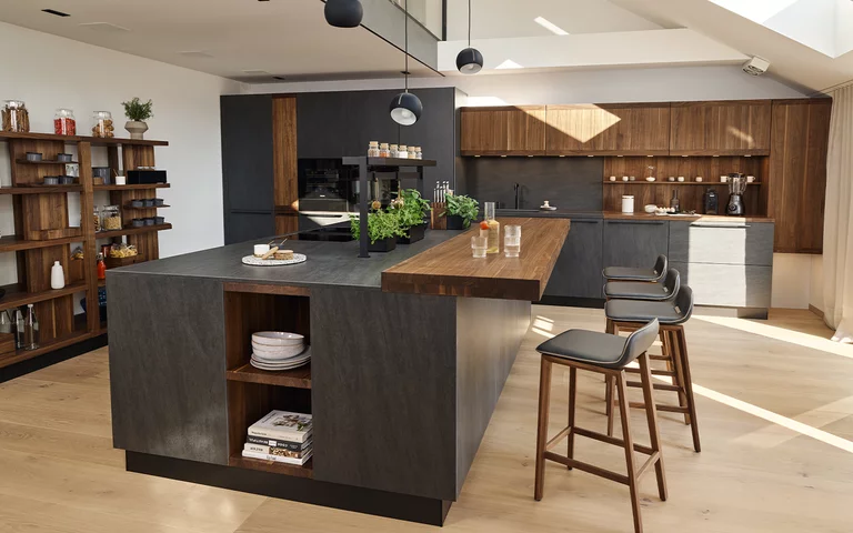 echt.zeit solid wood kitchen in walnut with basalt black ceramic and bar top with bar stools