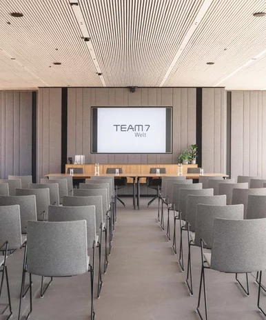 Veranstaltungsraum mit bestuhlten Sitzreihen und großem Bildschirm in der TEAM 7 Welt