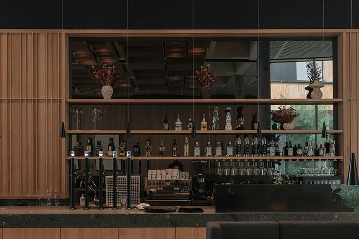 Elegant bar counter with ceramic worktop and Parsol mirror back panel in solid oak