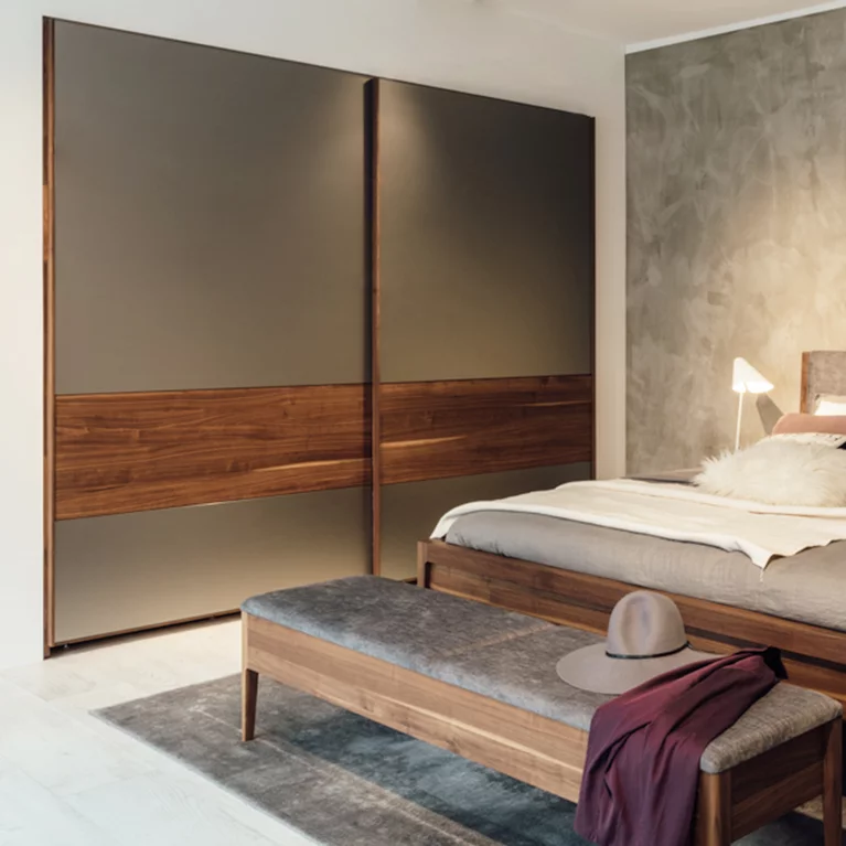 valore sliding door wardrobe with coloured glass fronts together with the mylon bed and the mylon bench in walnut wood