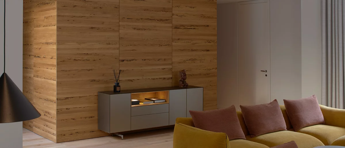 cubus pure sideboard with coloured glass casing on metal runners and illuminated oak niche in front of wooden wall in venetian oak