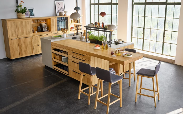 echt.zeit solid wood kitchen in oak with ceramic worktop and integrated dining area with ark bar stools
