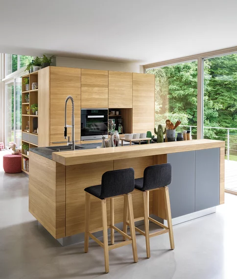 linee solid wood kitchen in oak with coloured glass fronts medium grey matt, worktop in natural stone and bar element with ark bar stools