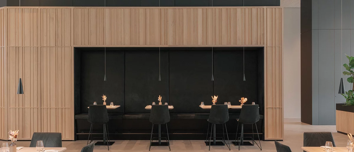 Elegante Restaurantsitzplätze mit lui Barstühlen und Massivholztischen in Eiche Naturöl