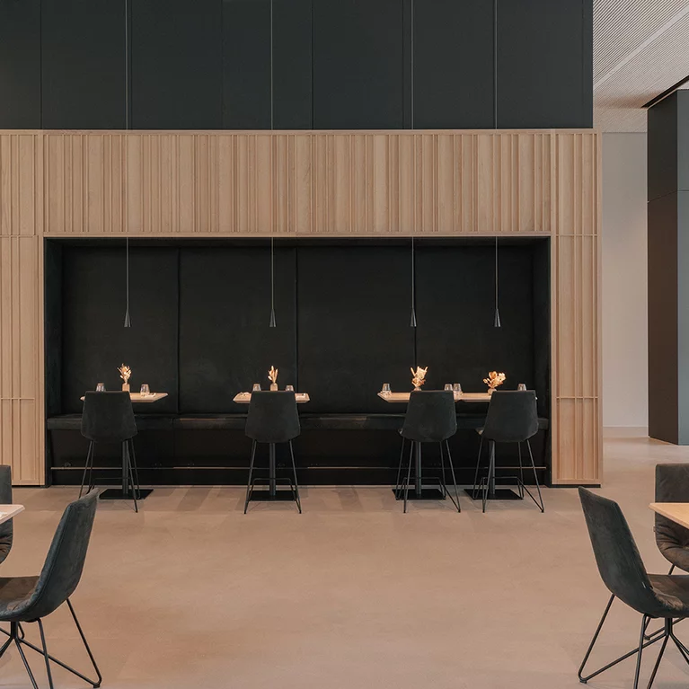 Elegante Restaurantsitzplätze mit lui Barstühlen und Massivholztischen in Eiche Naturöl