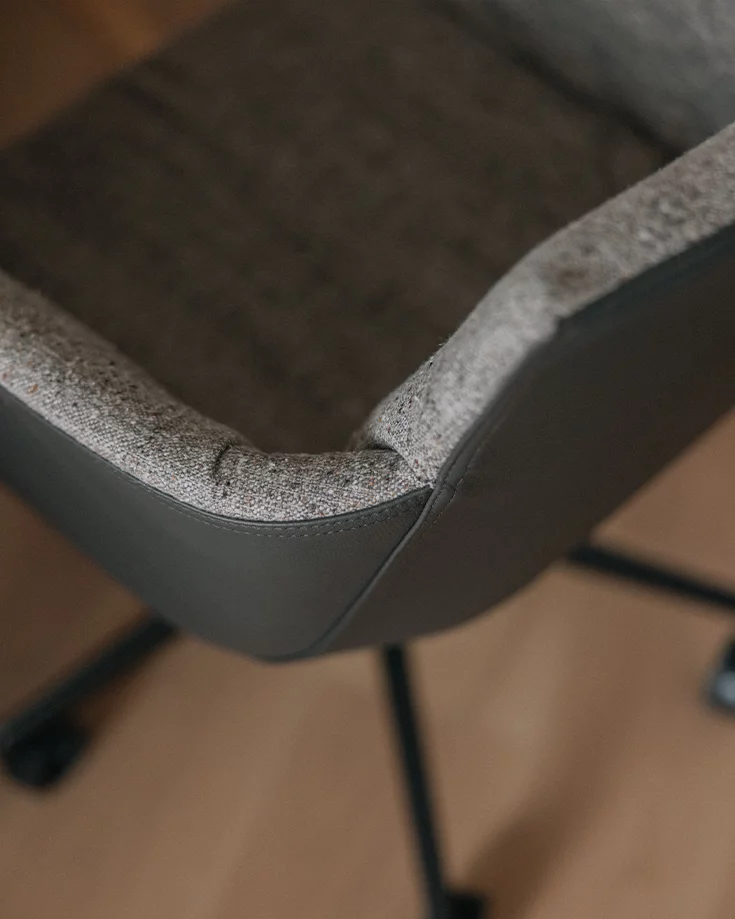 detailed view of grand lui office swivel chair with fabric upholstery inside and leather upholstery outside on swivel base with castors in black