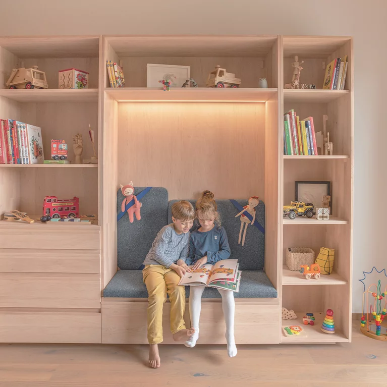 Kleiderschrank kids in Erle Weißöl mit großen Laden und gepolsterten Sitznische beleuchtet