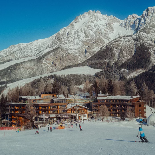 Holzhotel Forsthofalm in Leogang with mountain in the background directly on the ski slope