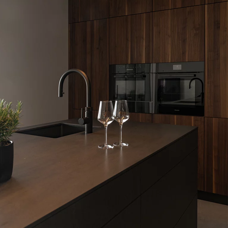 Elegante Kombination aus massivem Nussbaumholz, dunkler Keramik und schwarzen Küchengeräten Elegante Kombination aus massivem Nussbaumholz, dunkler Keramik und schwarzen Küchengeräten