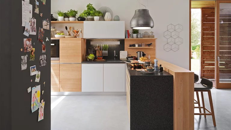 l1 natural wood kitchen in alder with coloured glass fronts, handle strips in stainless steel finish and bar element with ark bar stool